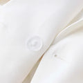 Close-up of white luxury office blazer fabric with button detail, featuring a classic style for women.