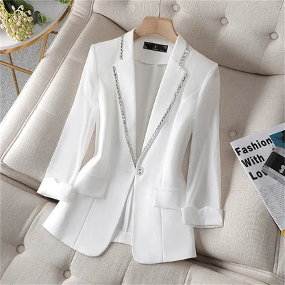 White women's blazer with paillettes, slim fit, and single button closure on a couch.