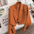 Women's loose solid color short suit jacket with notched collar and button decoration.